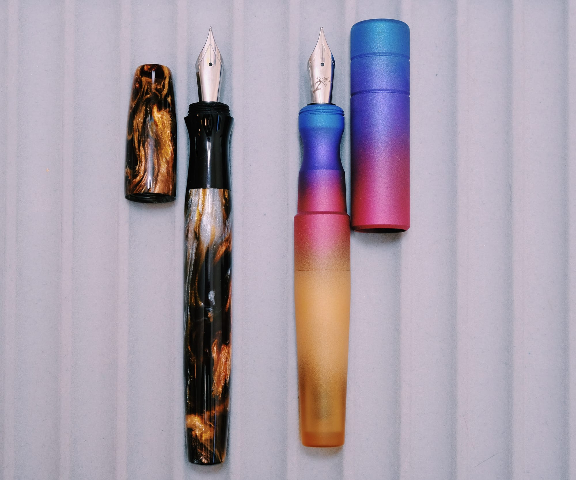 Mayfair Pens Noldor fountain pen uncapped on left, Kasama Una uncapped on right; the Una's "pinched" grip looking more narrow than the Noldor's