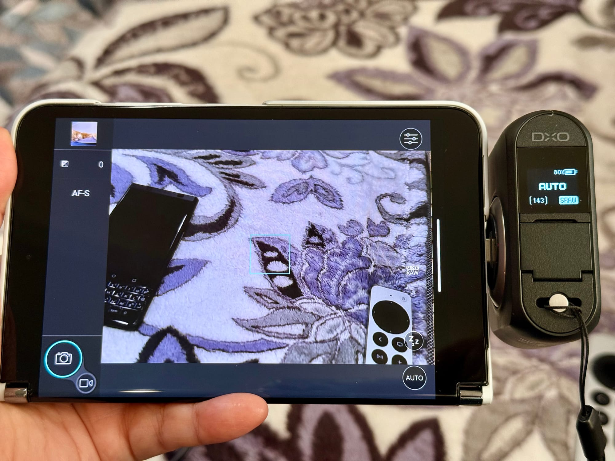 A Surface Duo 2, folded and held in landscape orientation, with the DXO One connected via USB-C, barely because of the obstruction of the "bumper" on the edge of the Duo 2