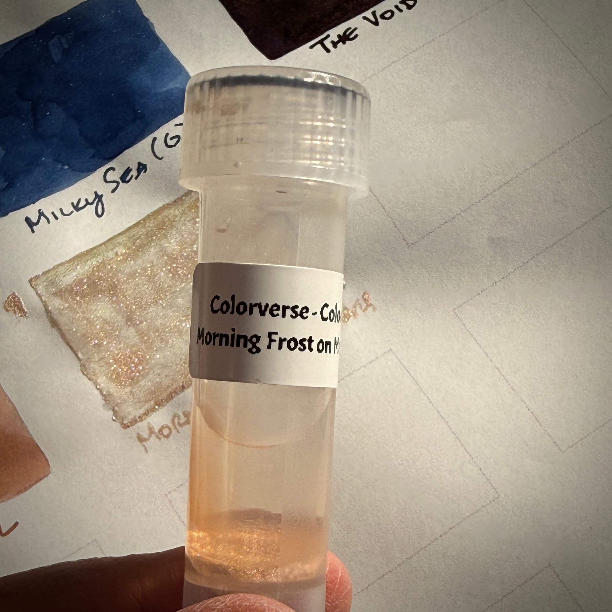 Close up on a plastic vial containing clear liquid and a thick layer of visible shimmer particles at the bottom