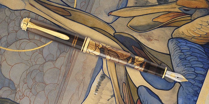 A Pelikan M600 fountain pen with gold trim, a translucent brown cap and grip section, and an artistic 