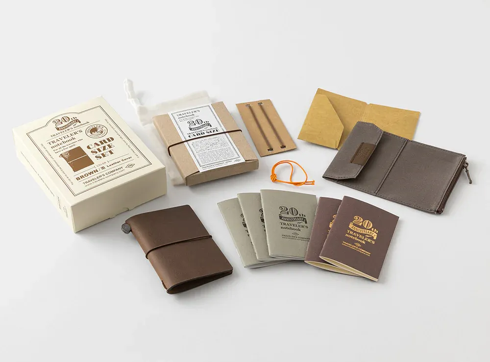 Full set of items in Traveler's Company card-size set: leather cover, 5 notebook inserts, 2 additional elastic bands, brown kraft cardstock folder, and canvas pocket with zippered section