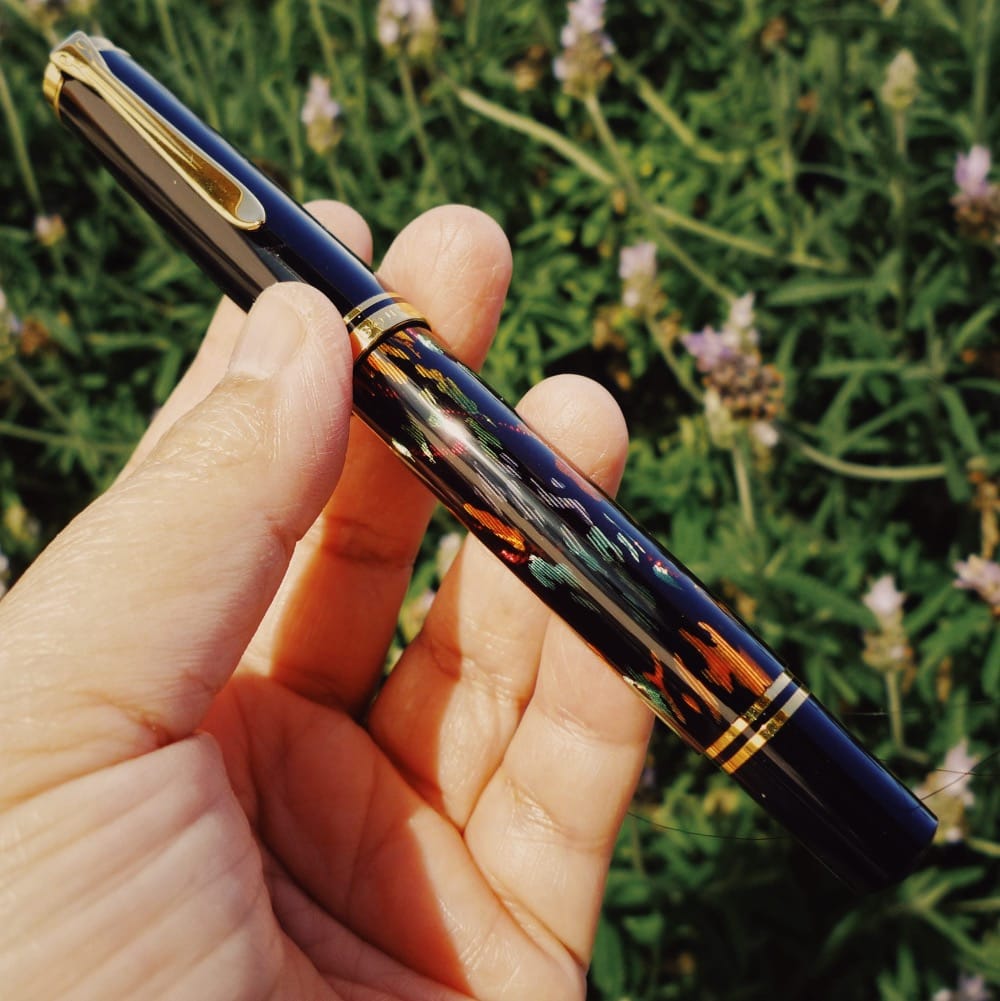 A Pelikan M600, black fountain pen with gold trim, and an organic, abstract multicolored design on the barrel