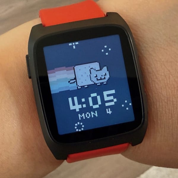 Close up of a watch with a black body and red watch band, with a Nyan Cat watch face showing the time, day of the week, and date