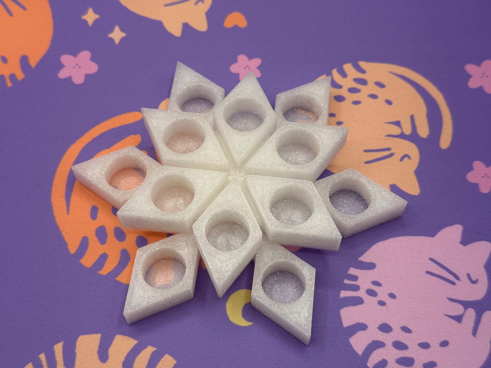 A white, shimmery snowflake-shaped stand with receptacles for 5 mL ink sample vials