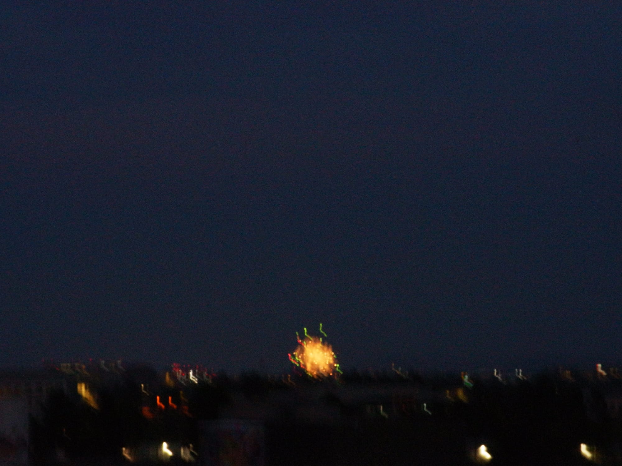 Motion blurred picture of a very small fireworks display far off in the distance