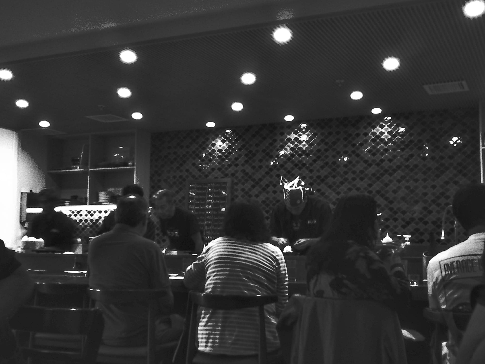 People sitting at a sushi bar, sushi chefs busy at work