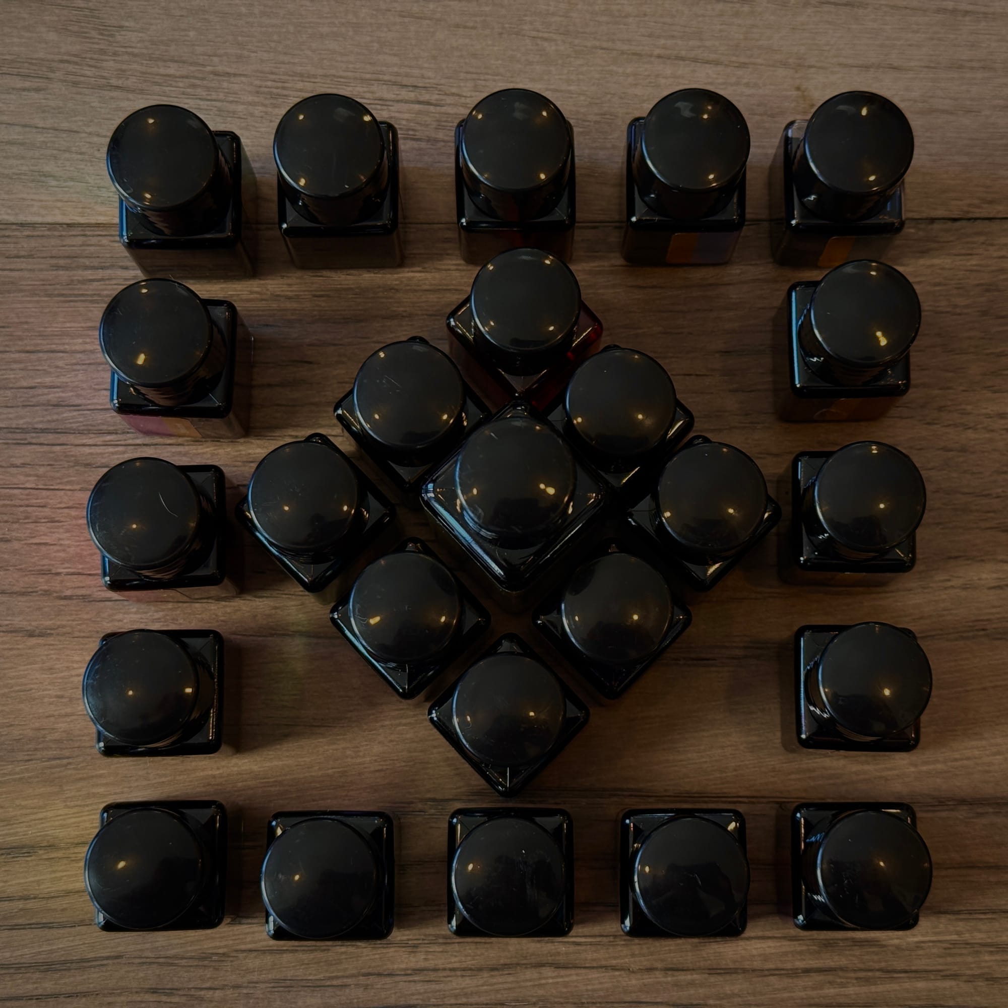 Square bottles rearranged with a wider-spaced 5x5 grid for the outer ring and the inner 9 bottles arranged in a diamond pattern, rotated 45º