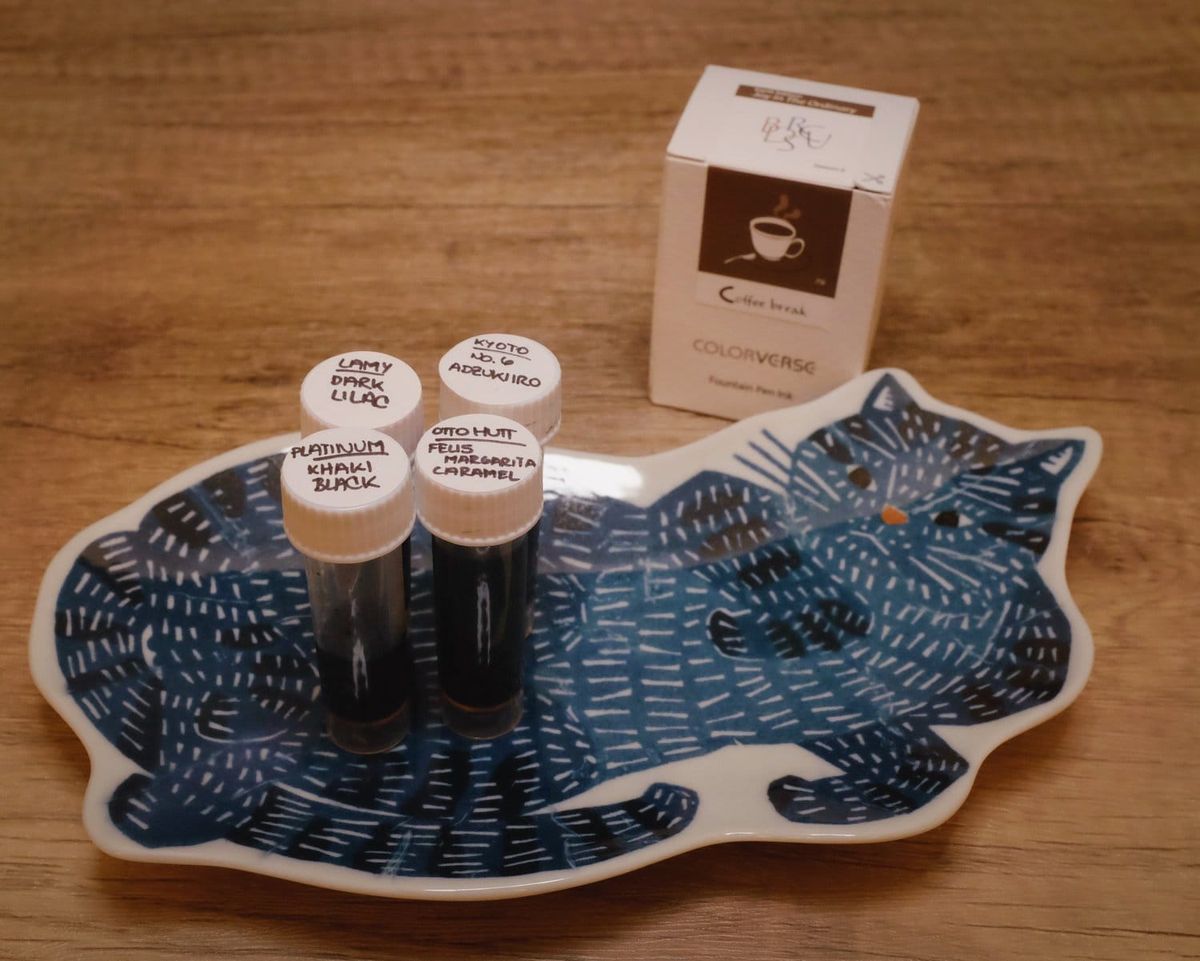 A large ceramic dish shaped as a blue cat has 4 fountain pen ink samples on it, boxed ink sitting behind