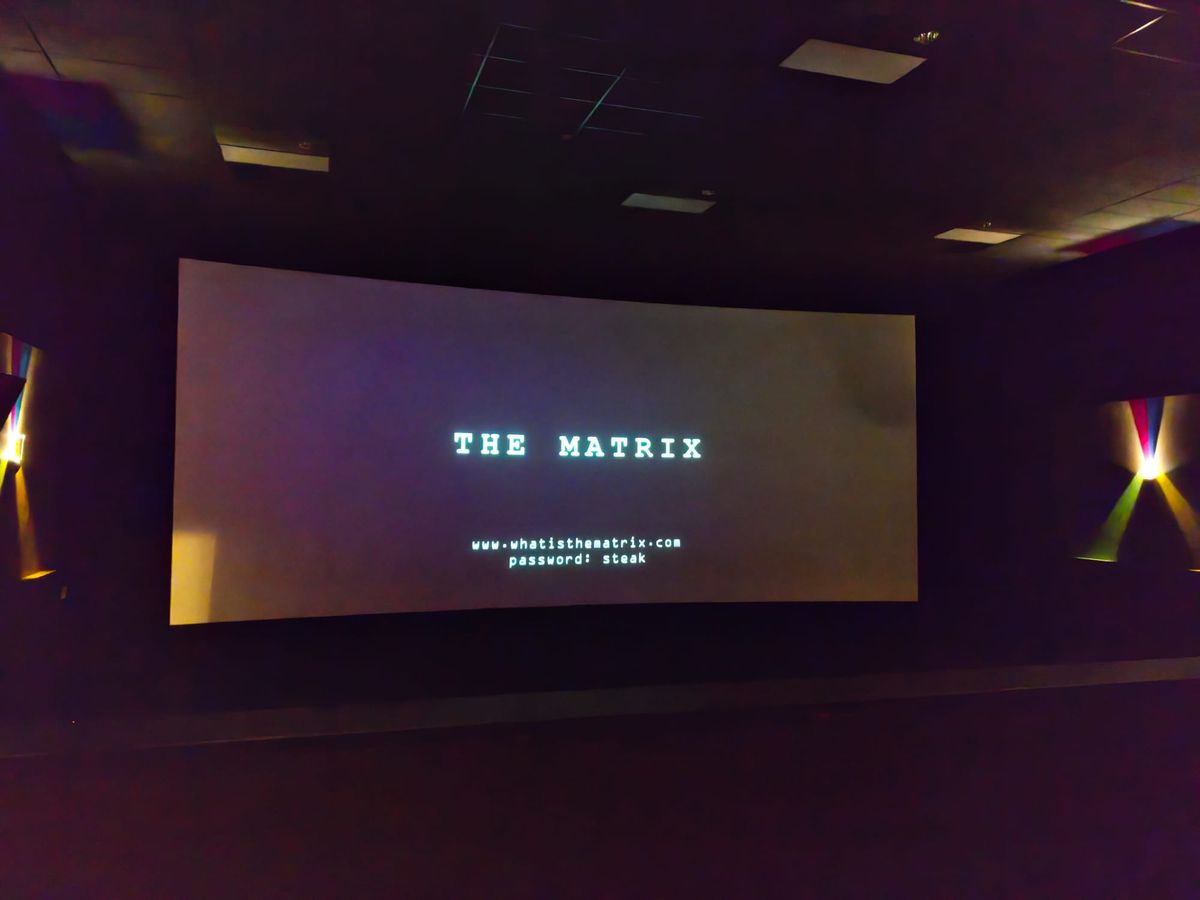 Movie theatre screen showing "The Matrix" and "www.whatisthematrix.com, password: steak"