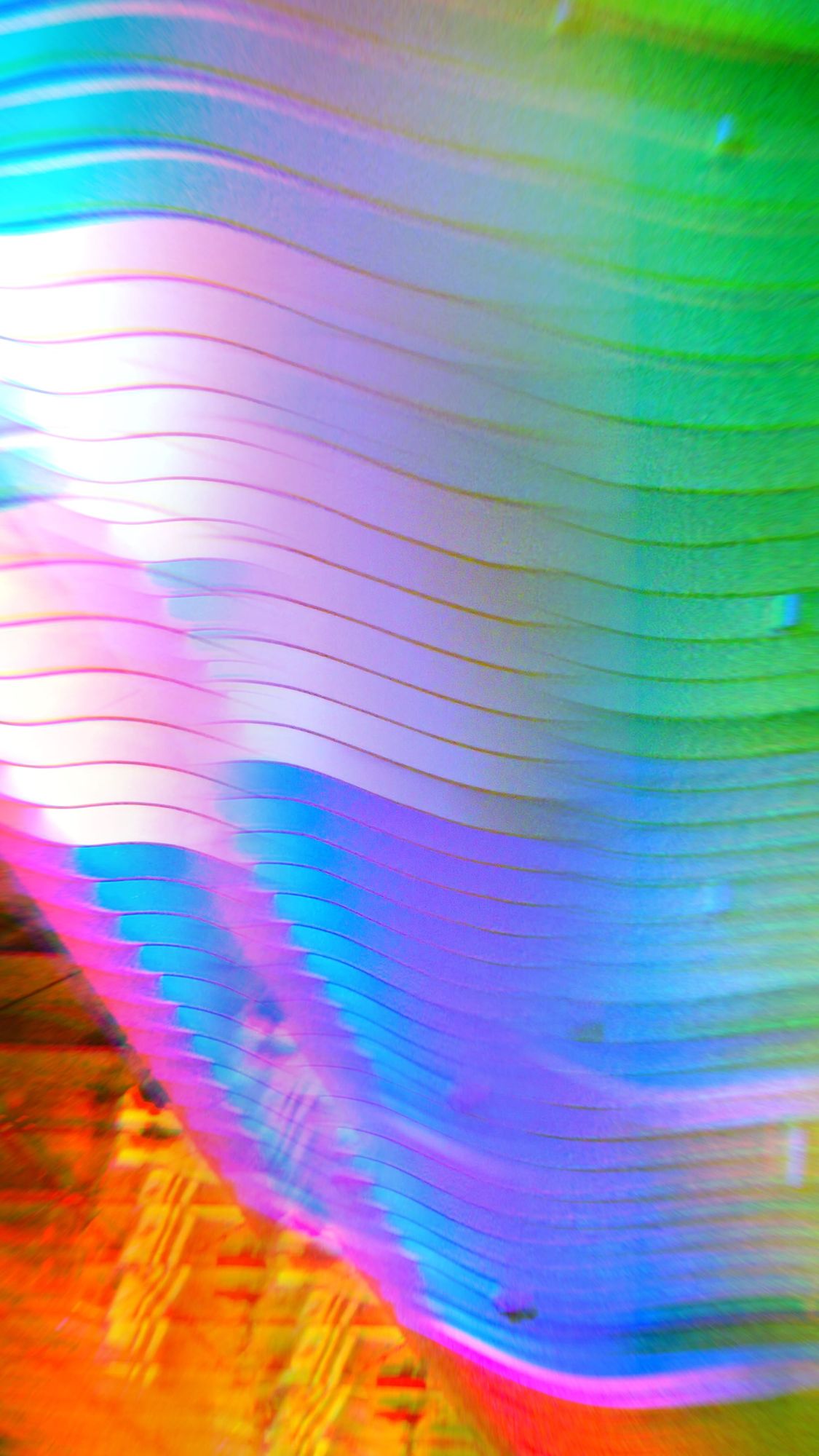 Abstract, kaleidoscope-like image of vivid, swirling colors and a blurred grid-like texture in the lower left