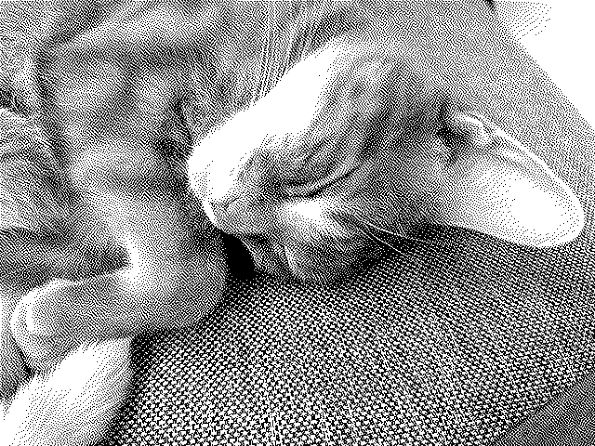 Low-res monochrome picture of a cat sleeping with his head upside down on a sofa cushion, his left ear not visible