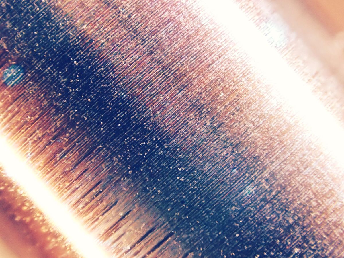 Abstract macro of a brightly lit metal cylinder with very tight parallel ridges angled diagonally in frame, oriented from bottom left to top right