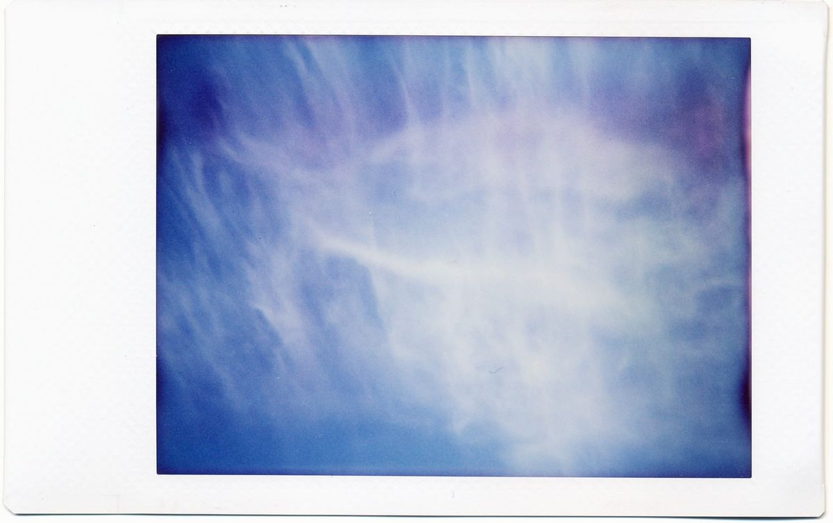 Wispy clouds forming an abstract pattern against a very blue sky, some film development aberrations manifesting as purple splotches along the right edge