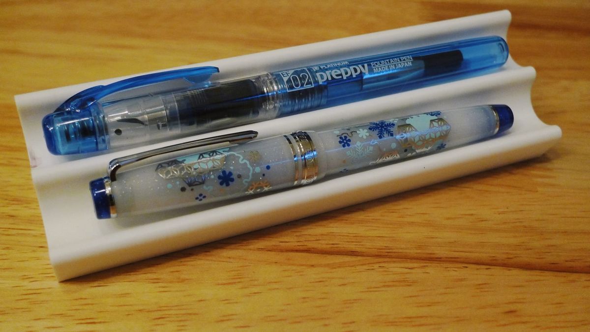 White 3D-printed dual pen tray with blue Platinum Preppy in top slot, Sailor Pro Gear Slim with snowflake design in bottom slot