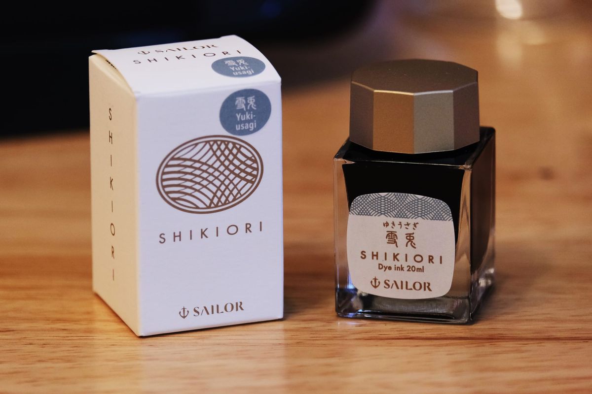 Sailor Shikiori Yuki-Usagi fountain pen ink bottle and box side by side on a wooden desktop