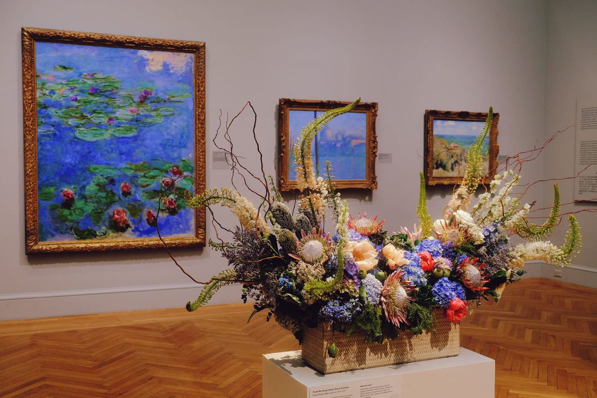 An elaborate floral arrangement sitting on a pedestal near Monet's water lilies painting on display at the Legion of Honor museum for Bouquets to Art 2025