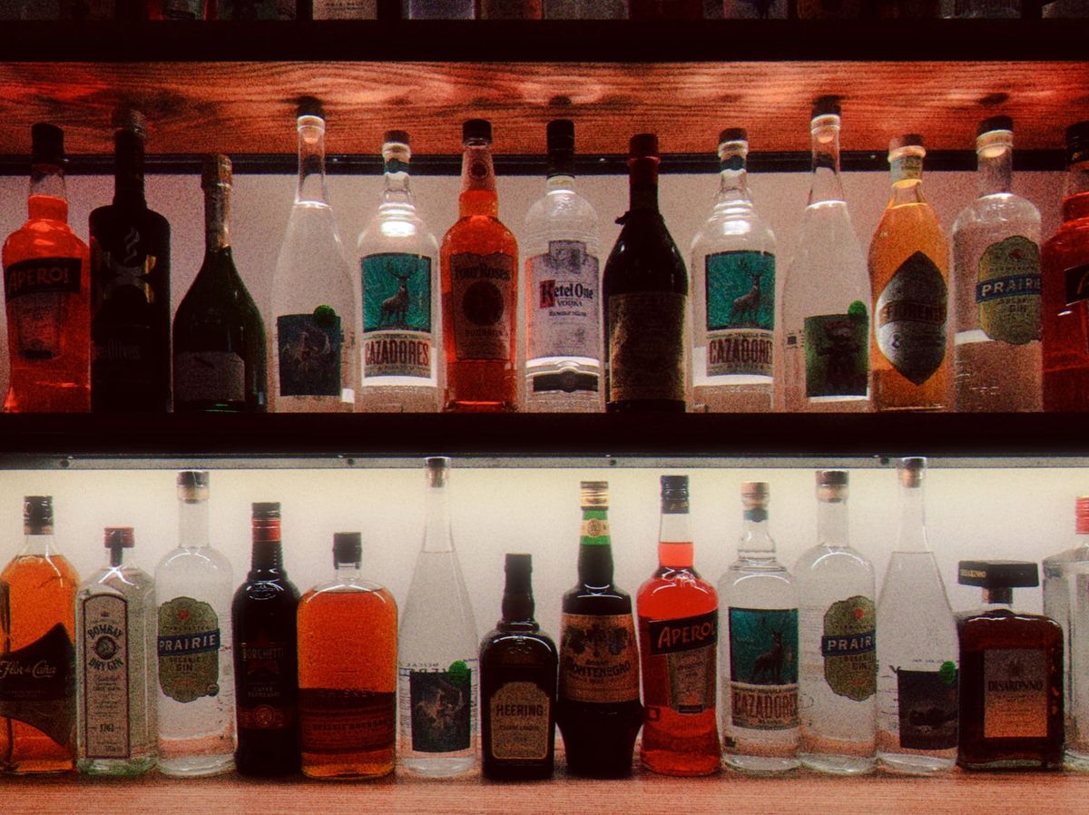 Grainy image of lit-up decorative shelves containing several different bottles of alcohol at a restaurant
