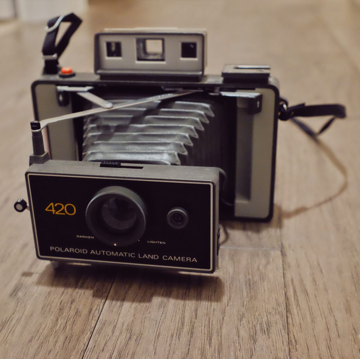 Close up of a Polaroid folding camera, the Polaroid Automatic Land Camera 420, sitting on a hardwood floor
