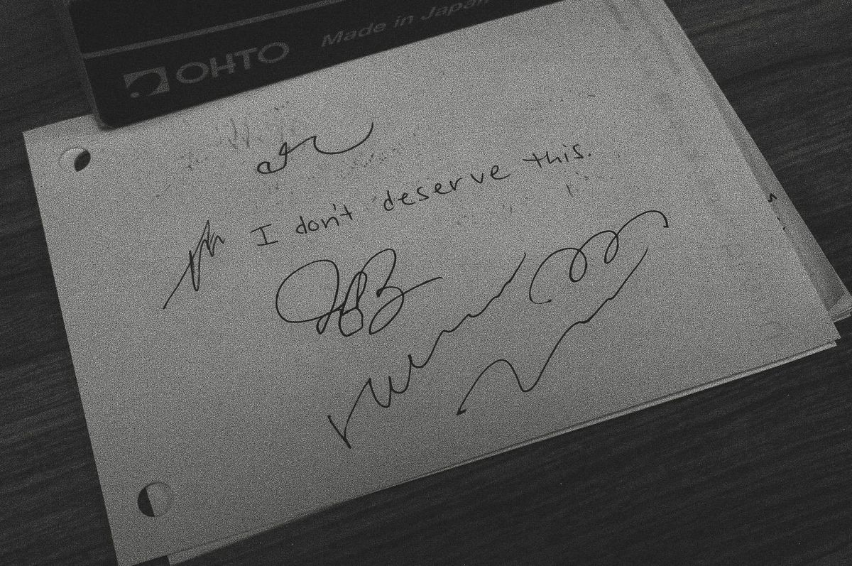 Black and white image of a scratch piece of paper at a pen testing station on which "I don't deserve this" along with random scribbles
