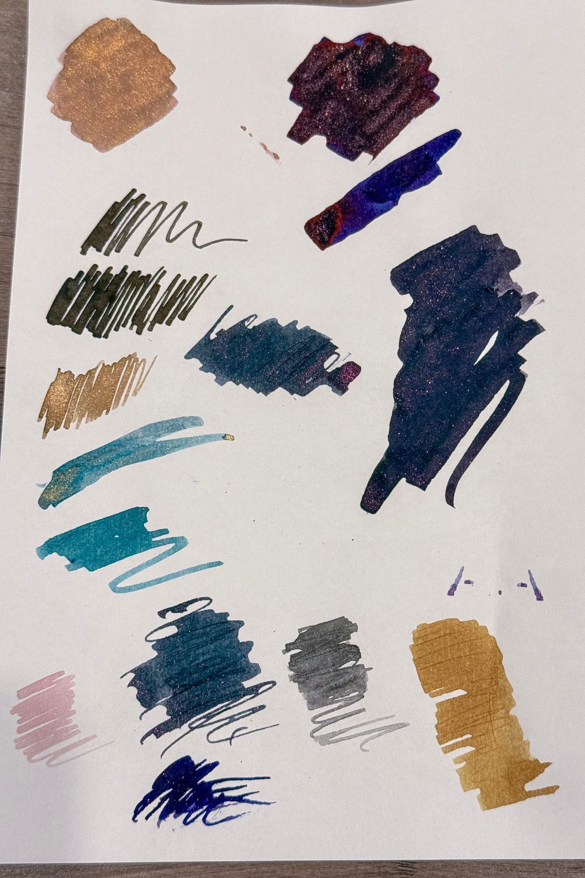 Fountain pen ink swatches of various colors and sizes randomly arranged on a piece of white paper