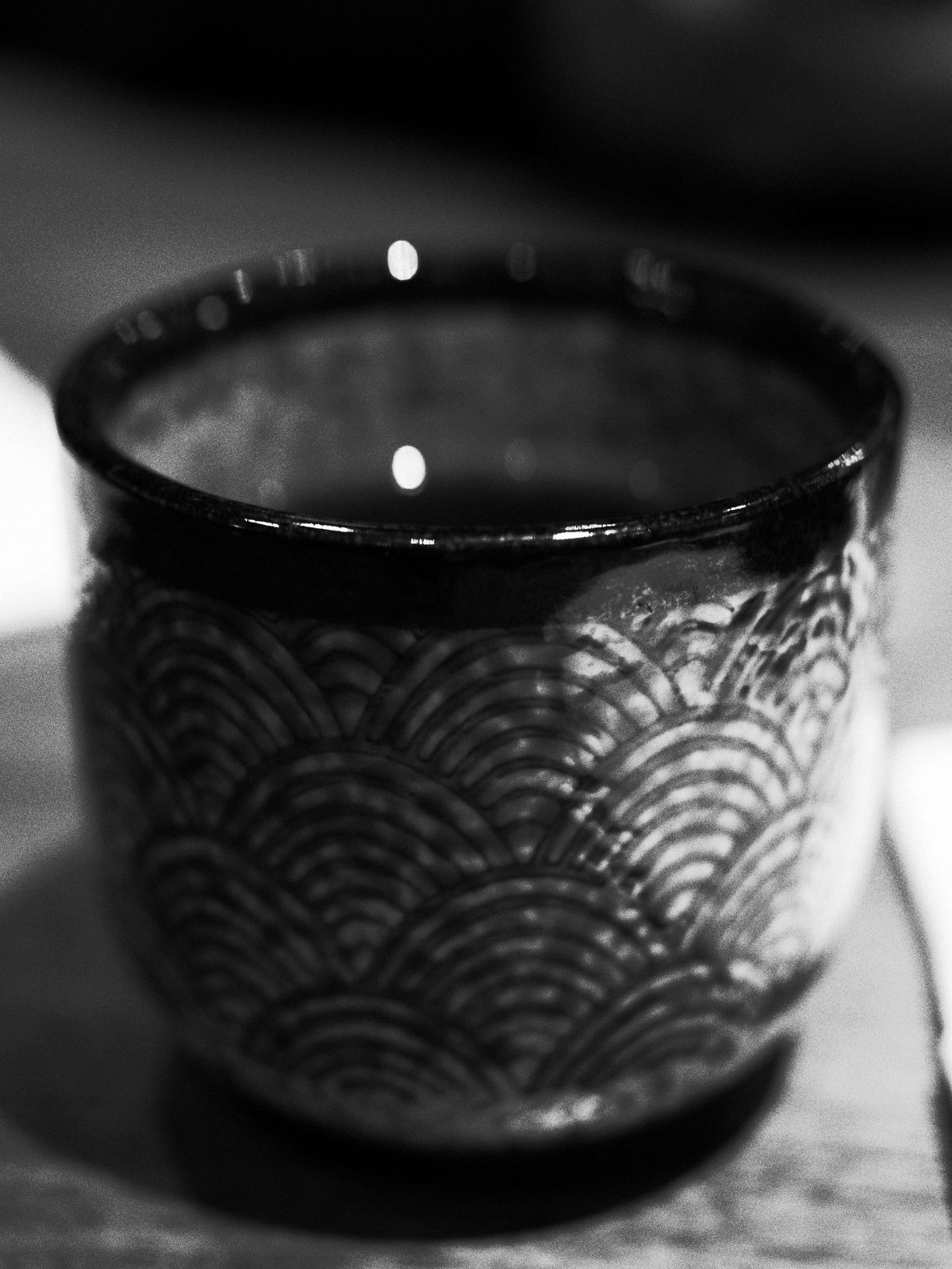 High-contrast black and white macro image of a Japanese tea cup with a traditional Japanese seigaiha pattern