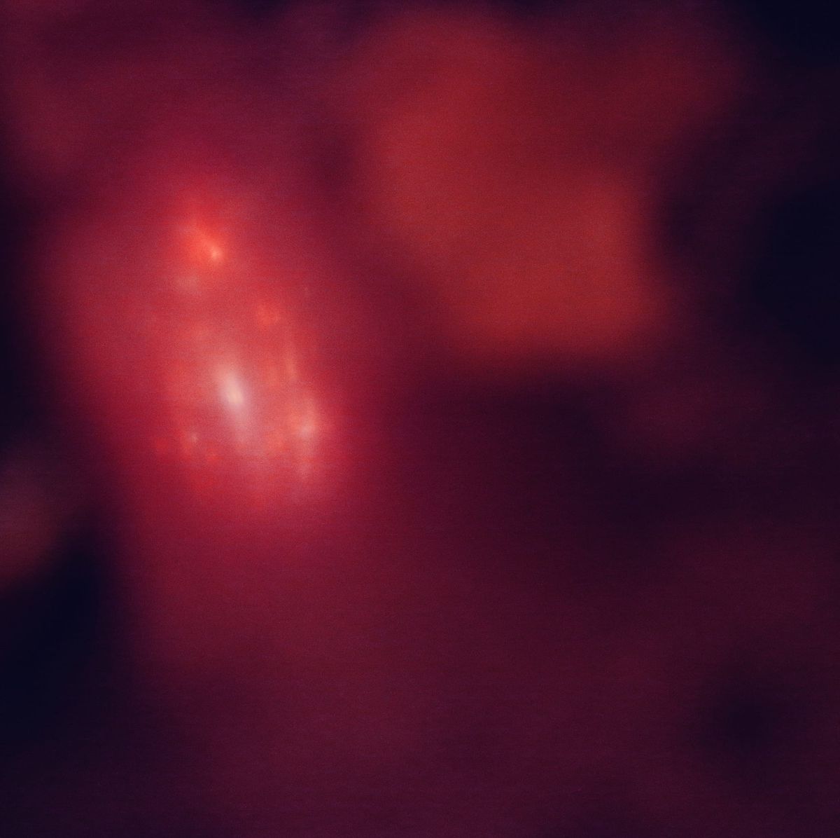 Abstract image, primarily red with organic areas of black around the edges, with a spacey, nebula-like object in the bright red area, upper left