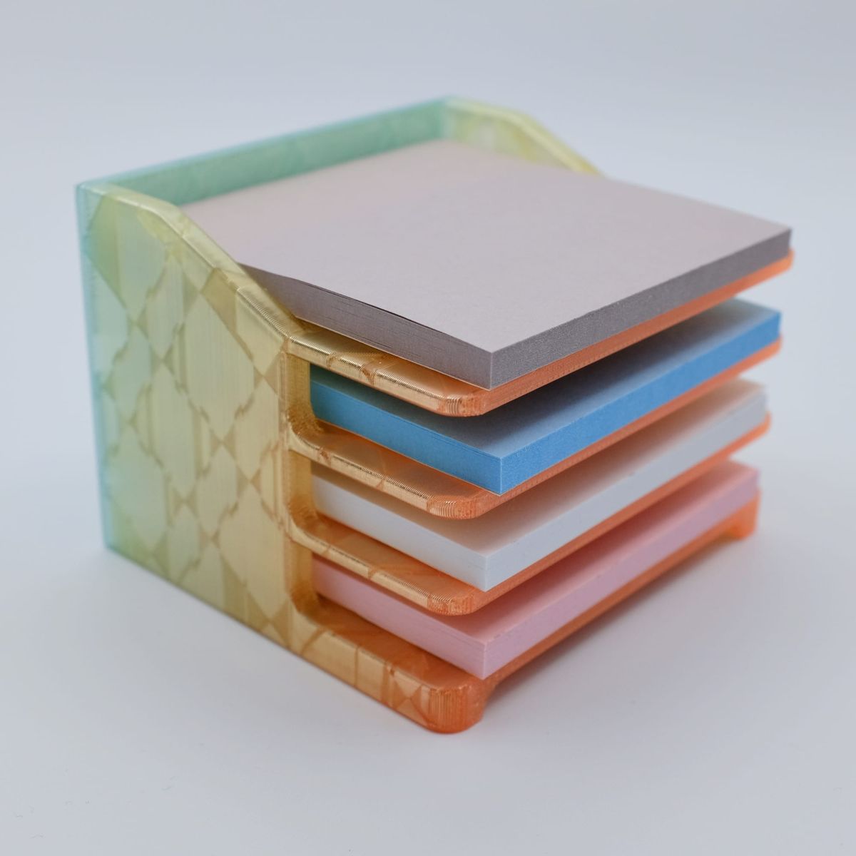 3D-printed, 4-tier Post-Its tray printed in a rainbow gradient filament shifting from light blue to orange, holding 4 different colors of Post-Its
