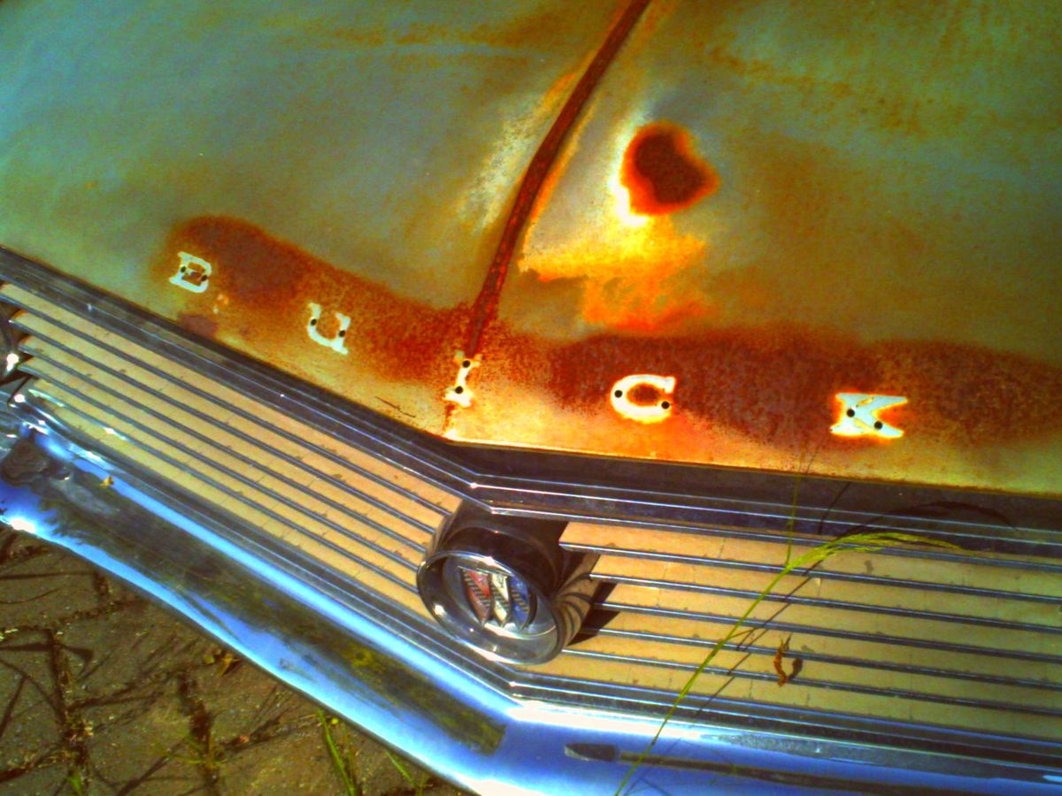 Low-res, lo-fi picture of the front of an old, rusty Buick showing its letters missing from the car hood