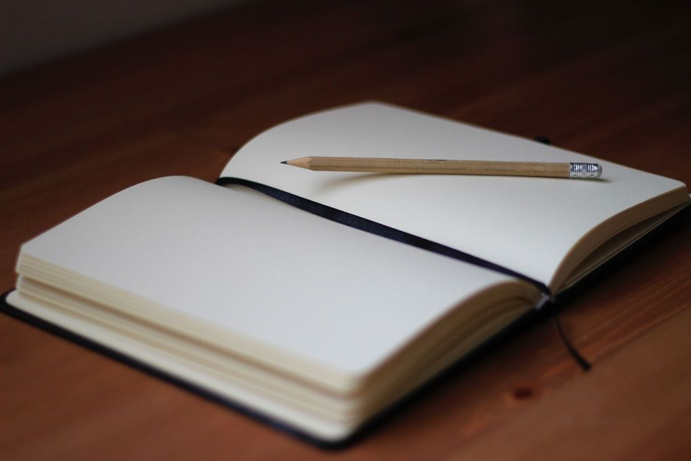 A pencil on an unlined notebook, which is opened to an empty page.