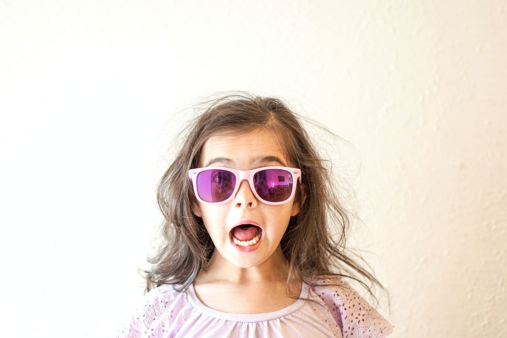 A very excited child wearing colourful sunglasses