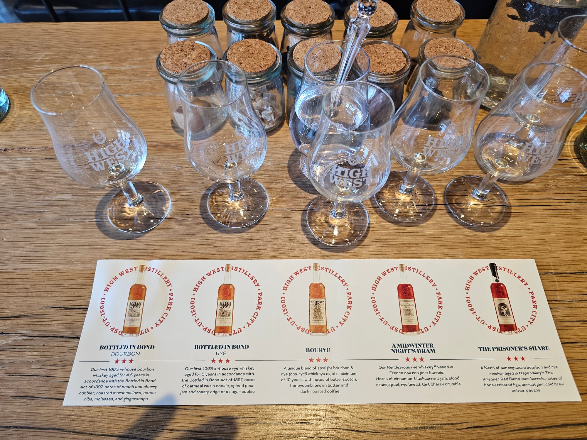 High West tasting glasses above a card listing Bottled in Bond Bourbon, Bottled in Bond Rye, Bourye, A Midwinter Night’s Dram, and The Prisoner’s Share
