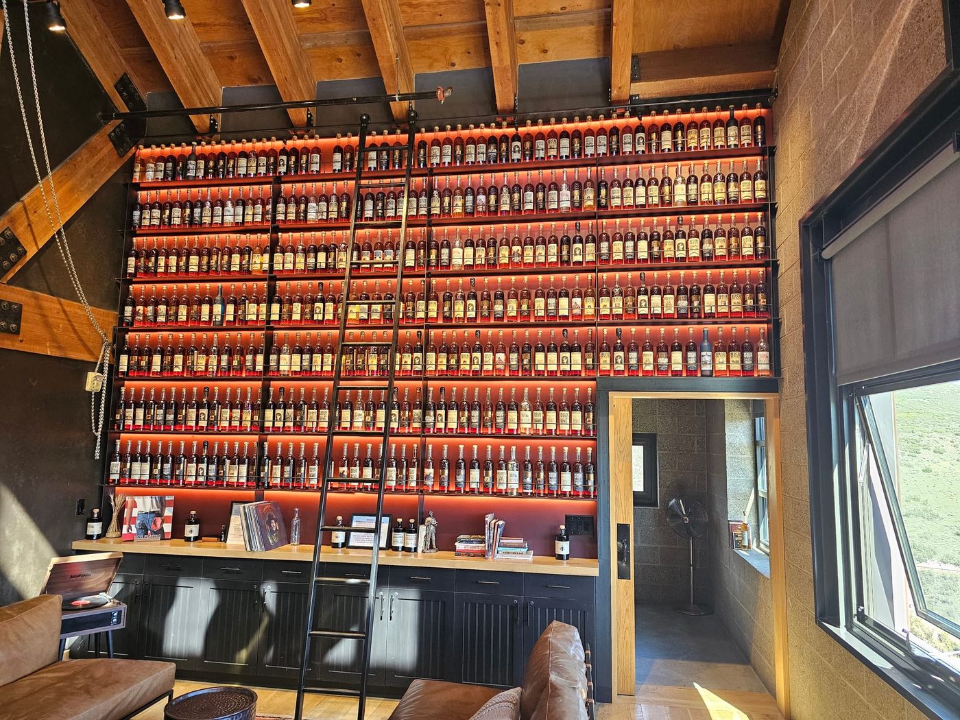 Illuminated shelves filled with High West bottles and a rolling ladder in the Whiskey Library