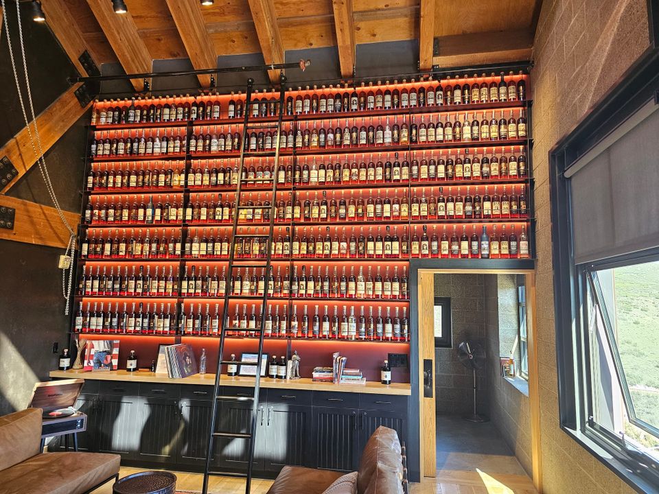 Illuminated shelves filled with High West bottles and a rolling ladder in the Whiskey Library