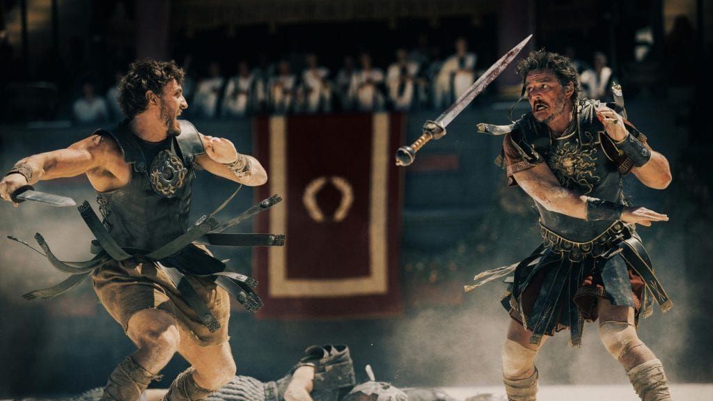 two men on each side of the screen in roman battle armor fighting with roman swords from Gladiator II