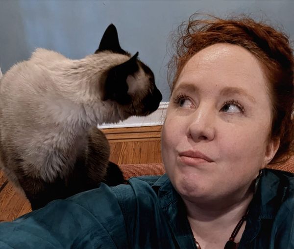 Sophie makes a kissy face at our terrible cat, Barnacle
