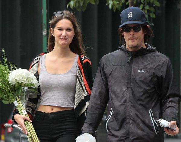 Norman Reedus walks down the street with a girl holding flowers