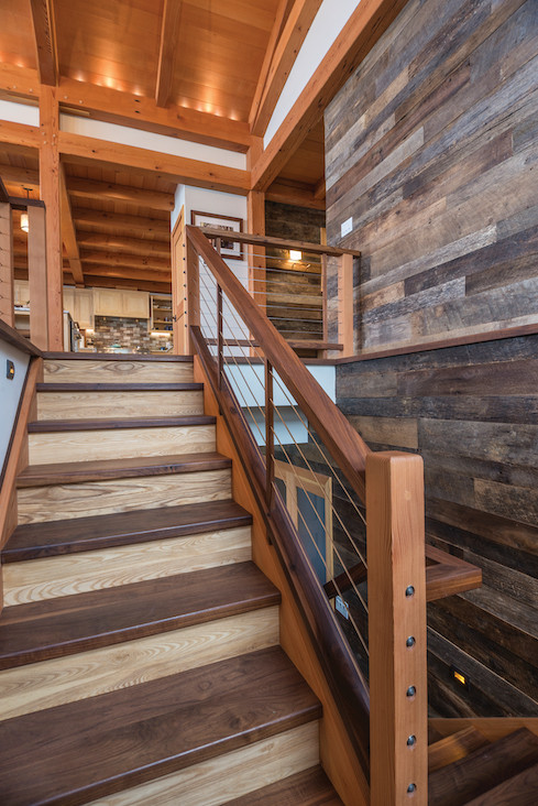 The custom staircase, crafted by NEWwoodworks, is made of walnut and ash, giving a two-toned appearance that complements the reclaimed wall paneling by Pioneer Millworks.