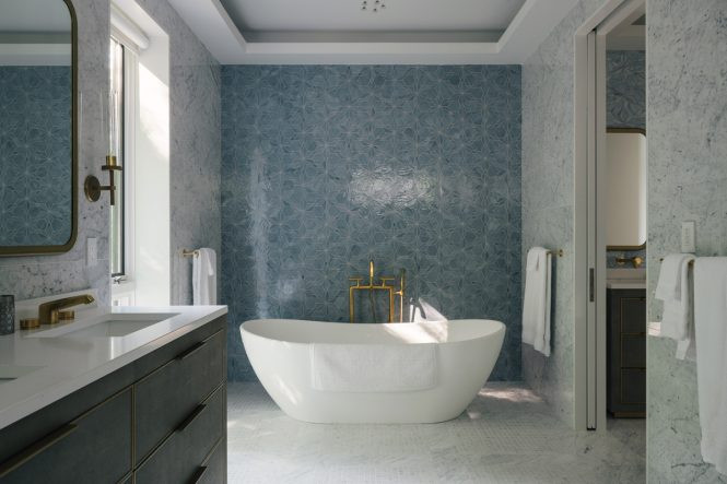 The home&rsquo;s main bathroom uses patterned gray and blue glass tiles as a contrast to white marble tub.