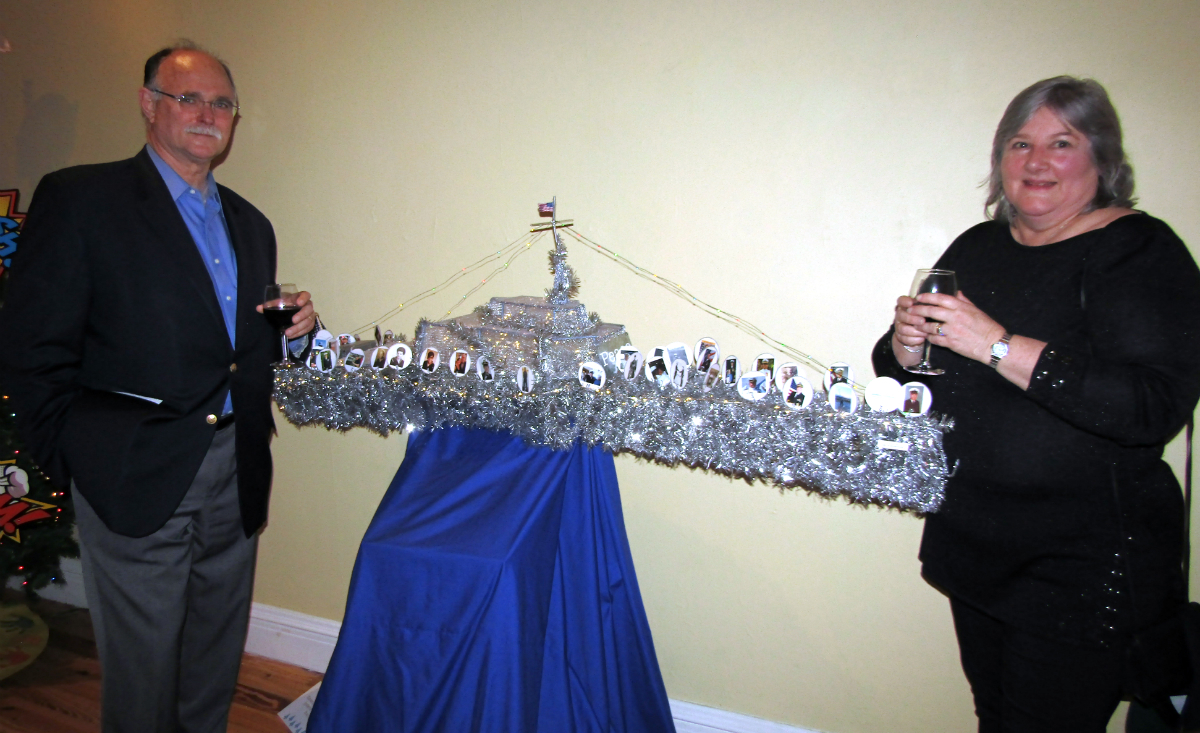 Phil Dore and Jill Dore, senior program manager of the General Dynamics Mission Systems&nbsp;Frigate Team, pose in front of the Team's battleship "tree" featuring photos of employees who served in the US Military.&nbsp;