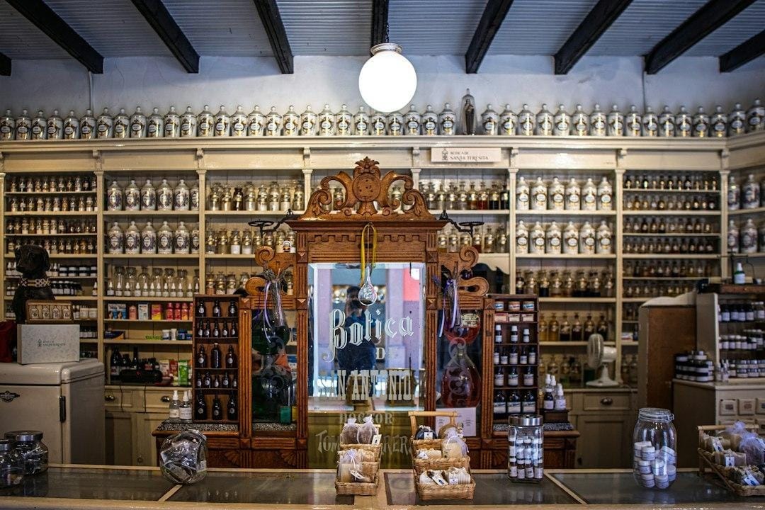 An old pharmacy interior with shelves of labeled glass jars and a wooden counter