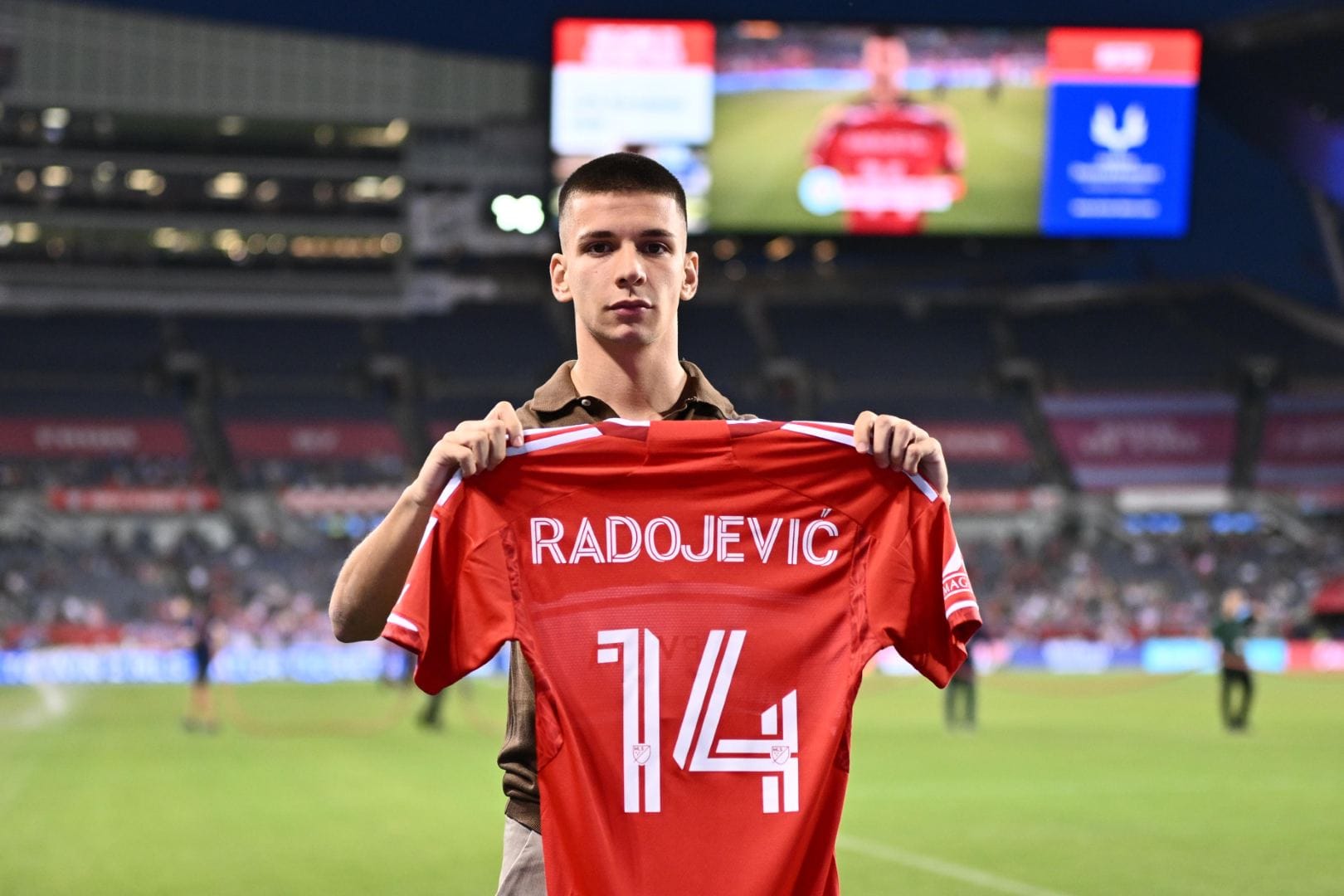 Viktor Radojević holds up a Chicago Fire jersey with his name and the number 14 during the Fire's game against NYCFC on September 13, 2025.