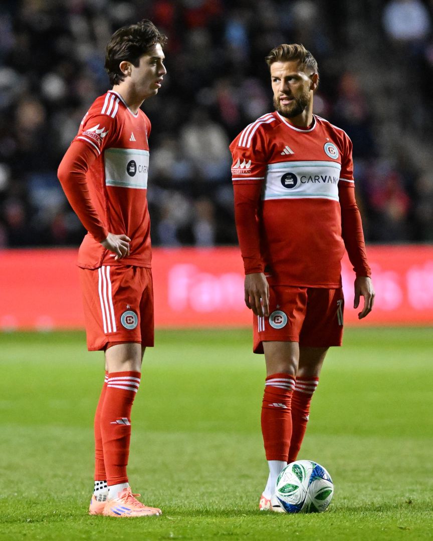 Brian Gutiérrez and Philip Zinckernagel stand over the ball in the Chicago Fire's playoff game against Orlando City at SeatGeek Stadium on October 22, 2025