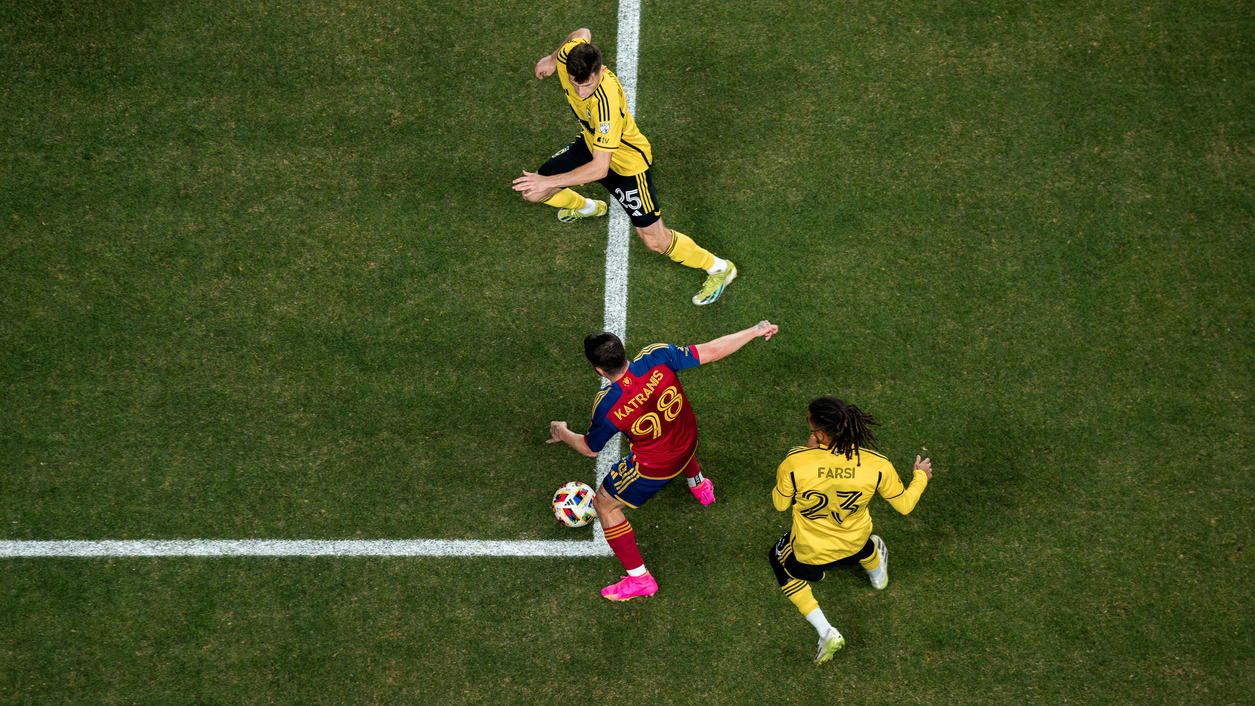 An overhead shot of three soccer players playing the ball during a soccer game