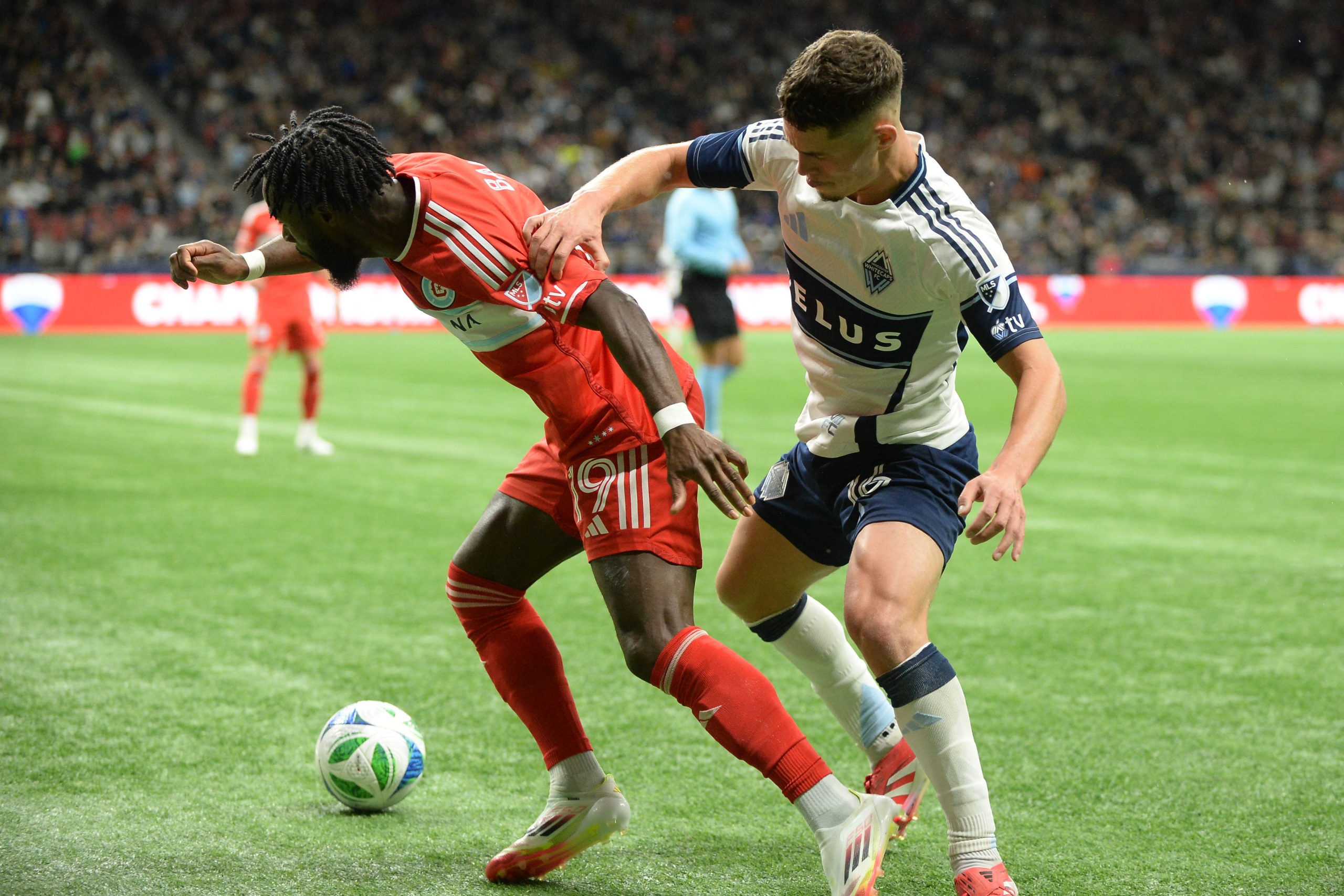 Mar 22, 2025; Vancouver, British Columbia, CAN; Chicago Fire FC forward Jonathan Bamba (19) defends against Vancouver Whitecaps FC defender Edler Ocampo (18) during the second half at BC Place. Mandatory Credit: Anne-Marie Sorvin-Imagn Images