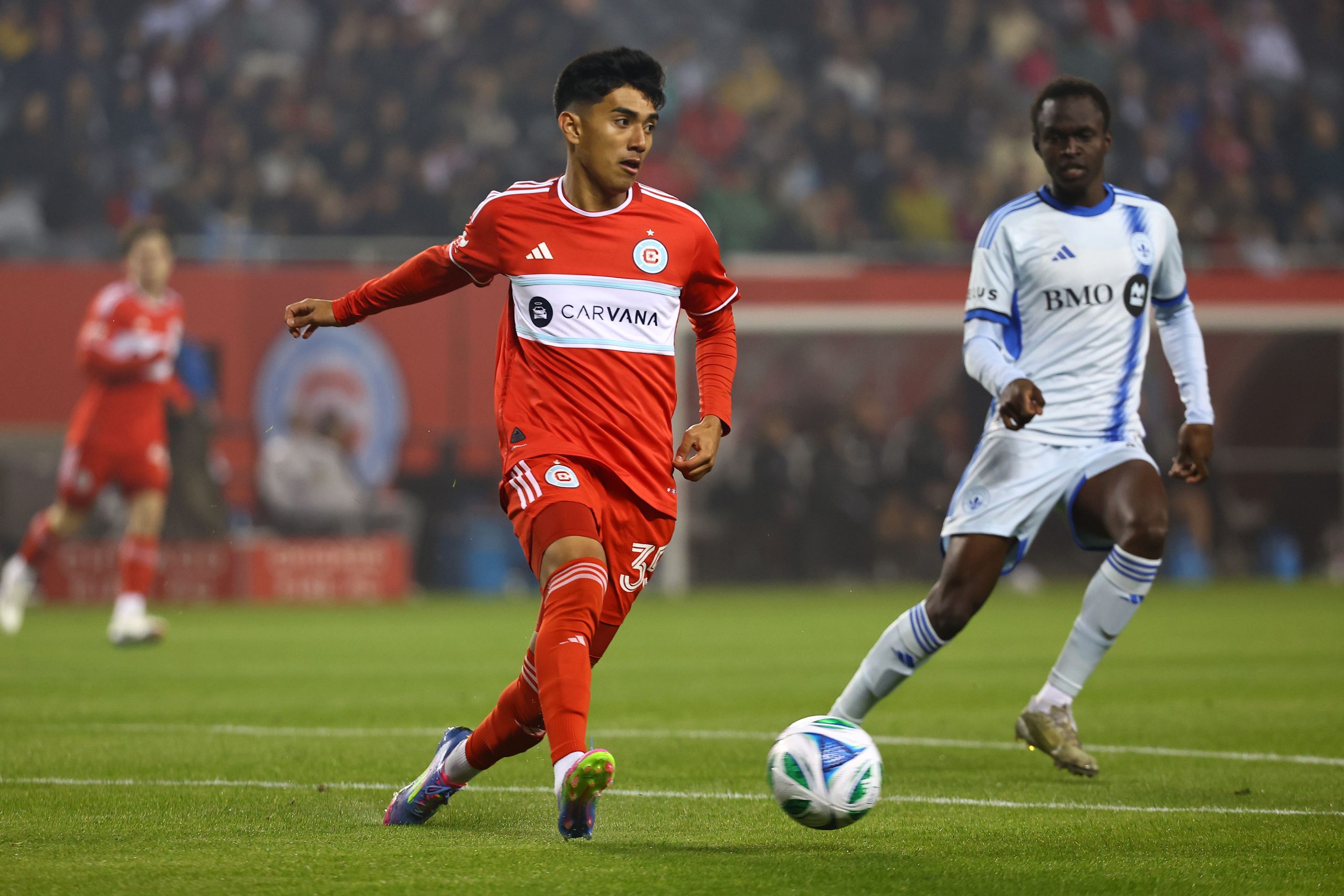 Mar 29, 2025; Chicago, Illinois, USA; Chicago Fire FC midfielder Sergio Oregel (35) kicks the ball past CF Montreal midfielder Victor Loturi (22) during the first half at Soldier Field. Mandatory Credit: Mike Dinovo-Imagn Images
