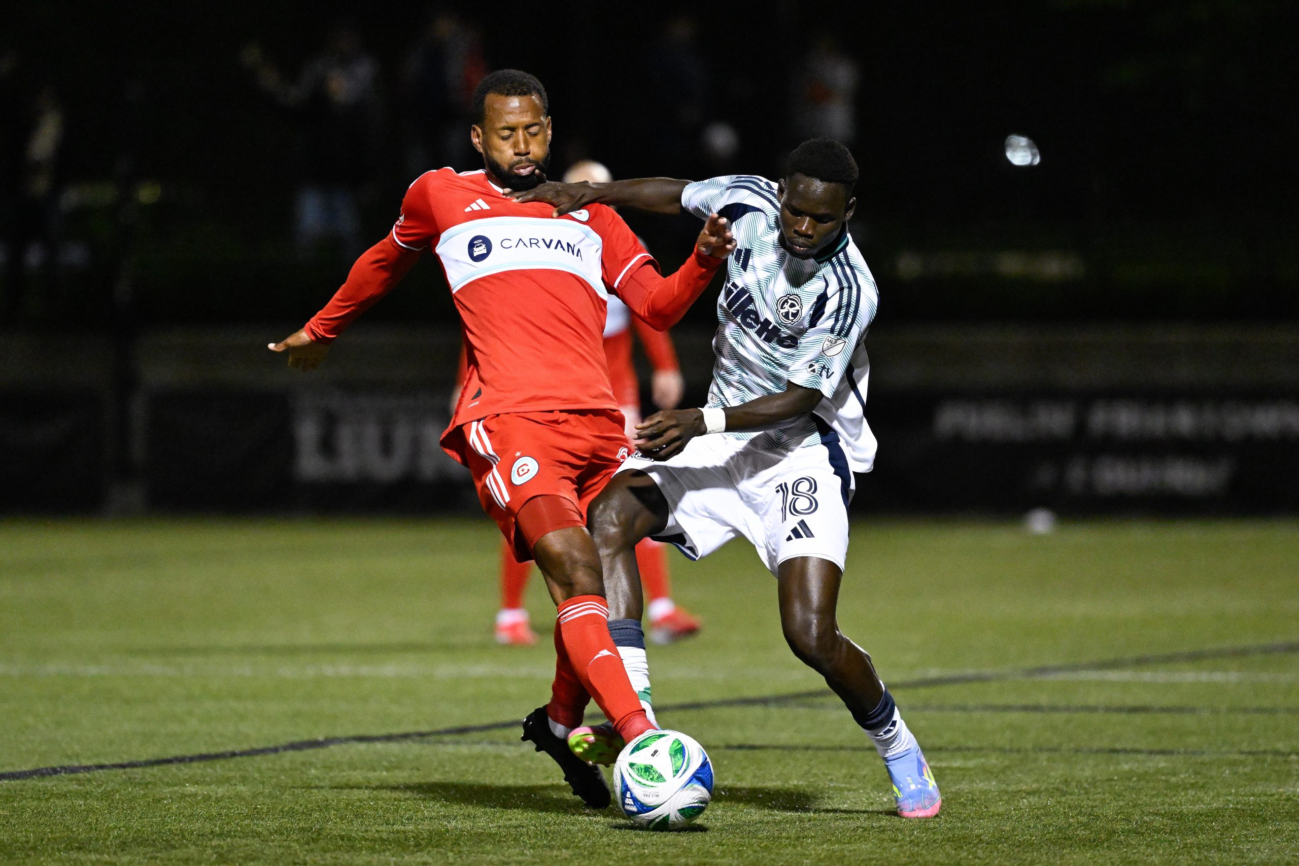 May 20, 2025; Providence, Rhode Island, USA; Chicago Fire midfielder Kellyn Acosta (23) and New England Revolution midfielder Allan Oyirworth (18) battle for control of the ball during the second half at Chapey Field at Anderson Stadium.