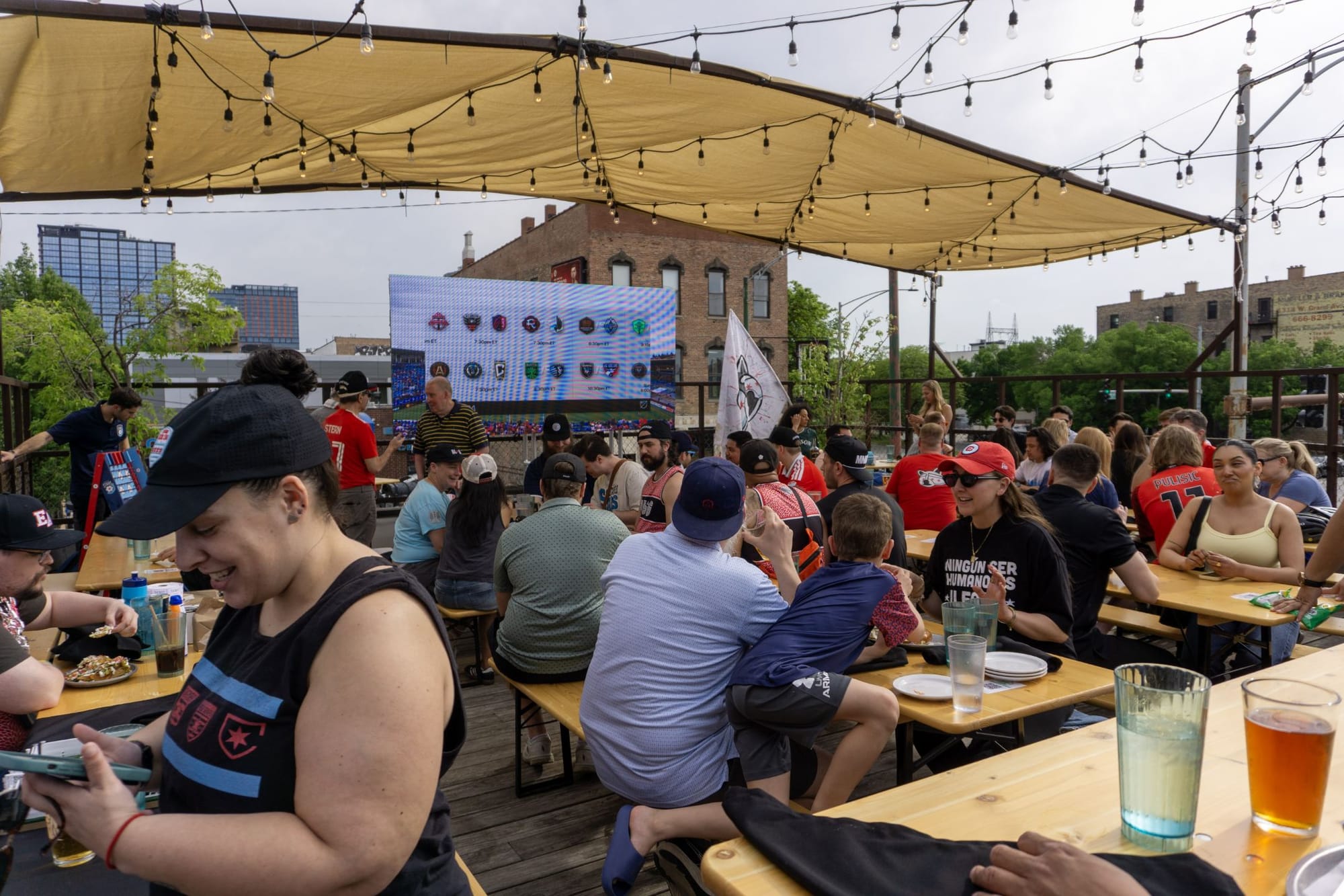 Picture of rooftop patio at Soccer House, showing the large TV and crowd.