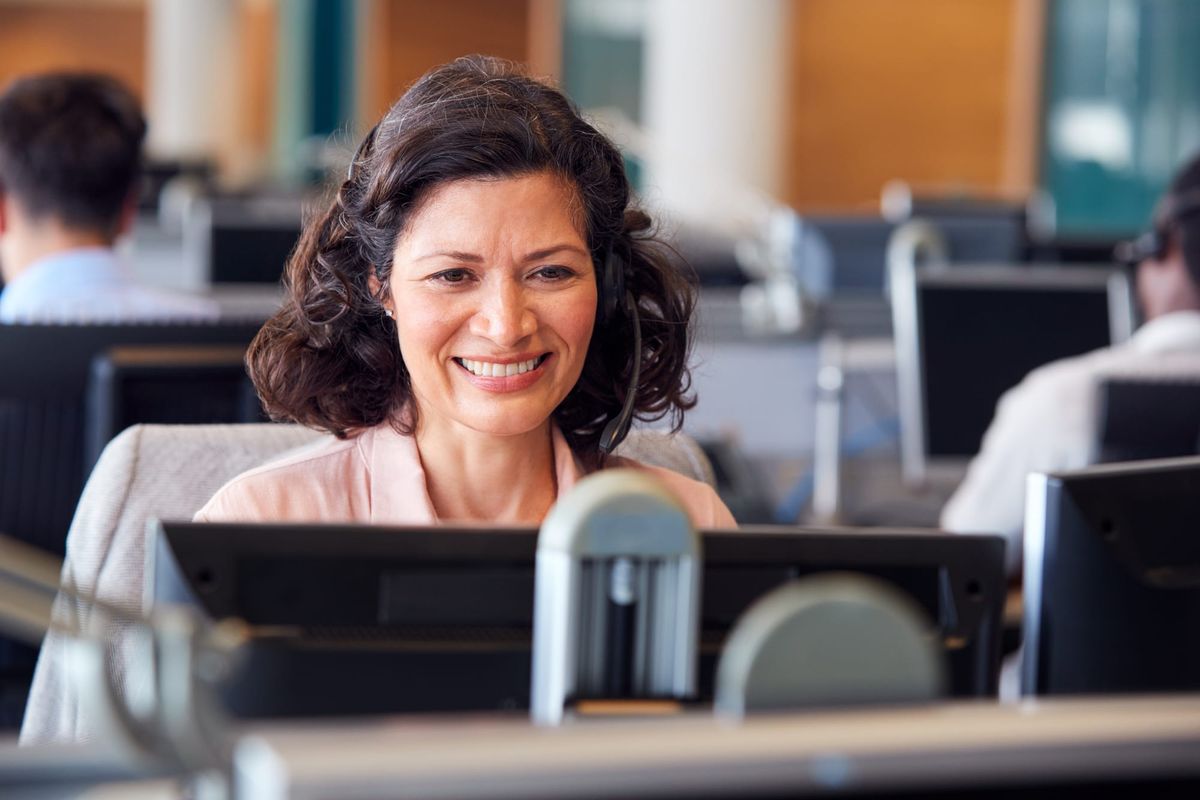 Smiling contact center manager at desk, highlighting the need for better leadership support in contact center managers
