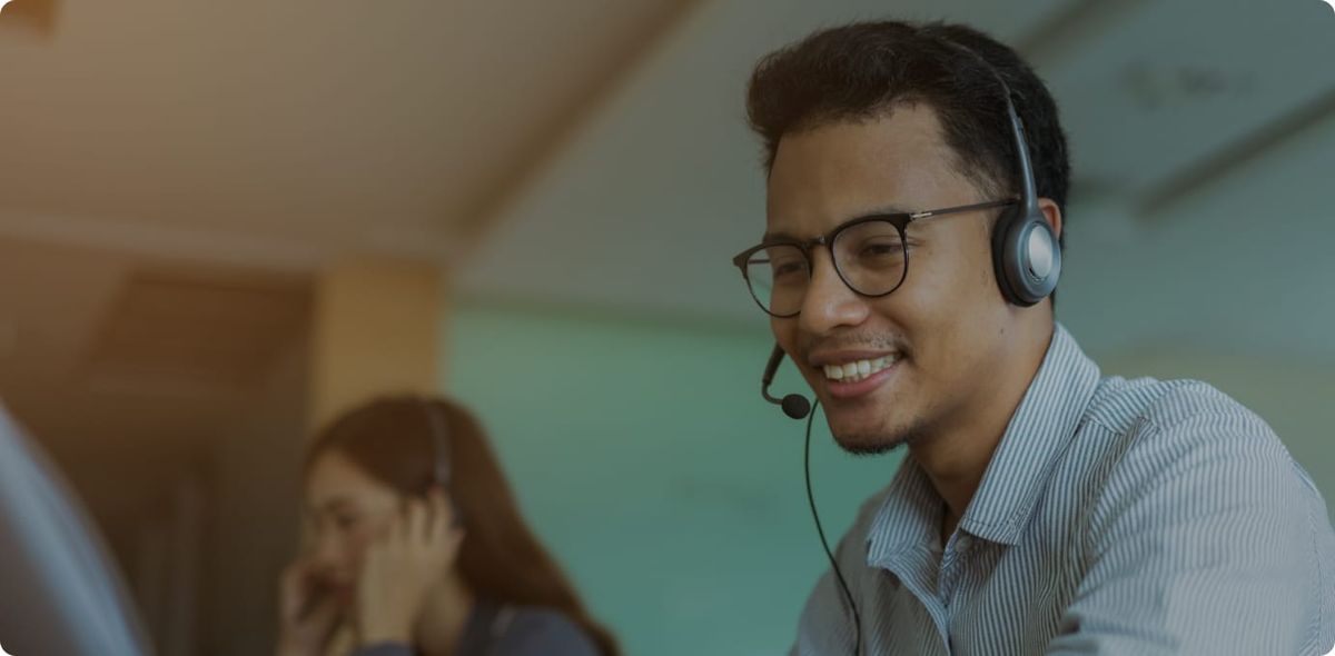 Smiling contact center agent with headset, reflecting positive leadership and coaching culture in modern contact centers