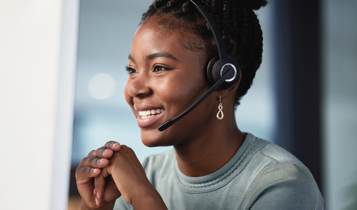 Smiling call center employee wearing headset, representing the benefits of upskilling in contact centers